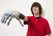 Photo: Young man looking at his prosthetic hand over gray background Young man looking at his prosthetic hand over gray background