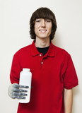 Photo: Portrait of a happy young man holding bottle with prosthetic hand over gray background Portrait of a happy young man holding bottle with prosthetic hand over gray background