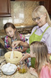 Senior woman with granddaughters mixing batter in kitchen