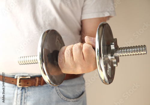 Photo: man holds a heavy weight in his hand man holds a heavy weight in his hand