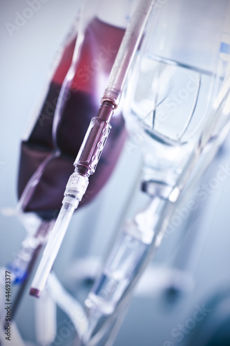 Photo: Bloody needle and bag with blood in the background. Bloody needle and bag with blood in the background.