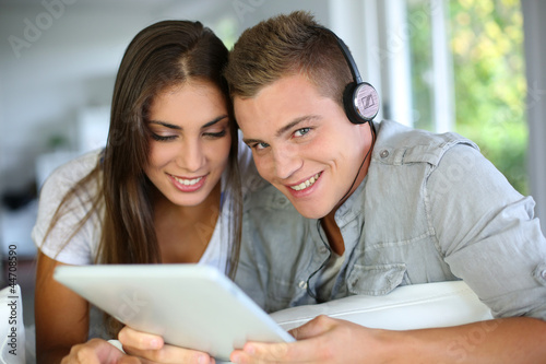 Photo: Young couple listening to music on electronic tablet Young couple listening to music on electronic tablet