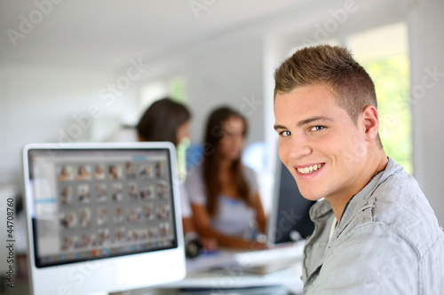 Foto: Young man sitting in office in front of desktop computer Young man sitting in office in front of desktop computer