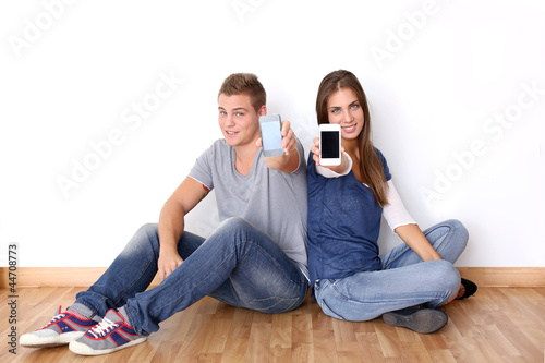 Photo: Teens showing mobile phones to camera Teens showing mobile phones to camera