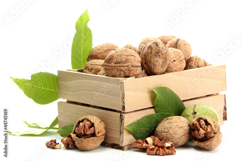 Photo: walnuts with green leaves in woooden crate, isolated on white walnuts with green leaves in woooden crate, isolated on white
