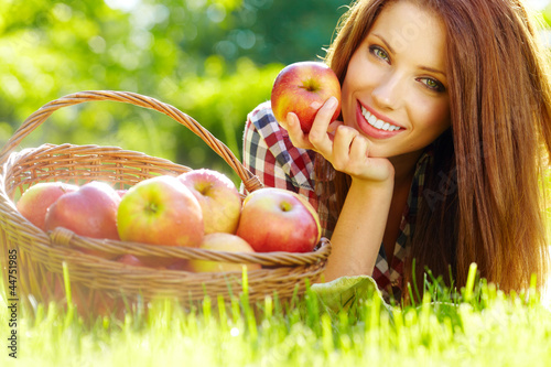 Photo: Beautiful woman in the garden with apples Beautiful woman in the garden with apples