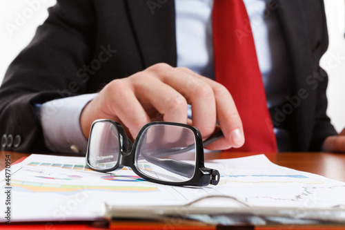 Photo: Businessman laying down his eyeglasses Businessman laying down his eyeglasses