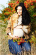 Portrait of beautiful pregnant woman walking in autumn park