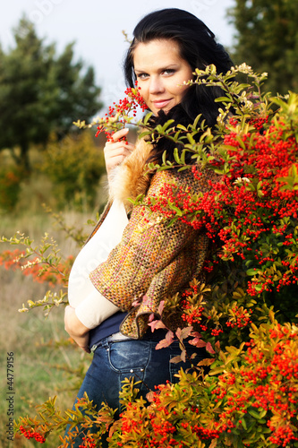 Photo: Portrait of beautiful pregnant woman walking in autumn park Portrait of beautiful pregnant woman walking in autumn park