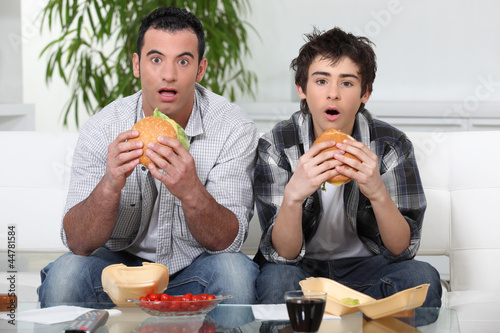 Foto: Brothers staring in amazement while eating a hamburger Brothers staring in amazement while eating a hamburger