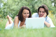 Couple lying on the grass looking at a laptop computer screen