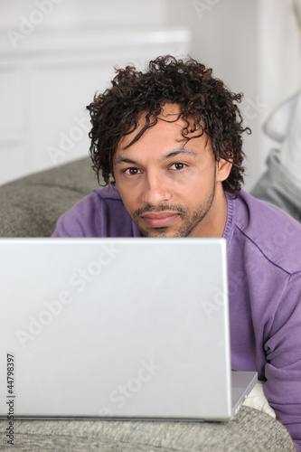Photo: half-caste man with laptop in flat half-caste man with laptop in flat