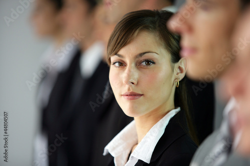 Photo: Young woman standing in line with co-workers Young woman standing in line with co-workers