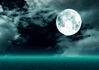The full moon in the night sky reflected in water