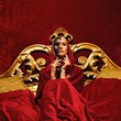 Beautiful woman with a carnival mask sitting in bed