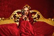 Beautiful woman with a carnival mask sitting in bed