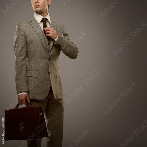 Photo: Businessman with a briefcase isolated on grey Businessman with a briefcase isolated on grey