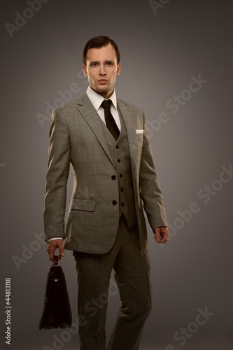 Photo: Businessman with a briefcase isolated on grey Businessman with a briefcase isolated on grey