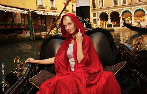 Photo: Beautiful woman in red cloak riding on gondola Beautiful woman in red cloak riding on gondola