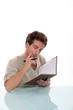 Pensive man writing in book