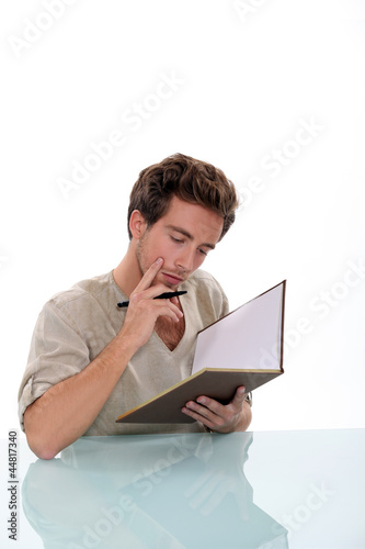 Photo: Pensive man writing in book Pensive man writing in book