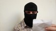 Man with Black Balaclava Reads Paper