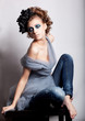 Casual modern woman with blue make-up sitting in jeans