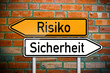 Wegweiser auf Ziegelsteinwand mit Risiko und Sicherheit