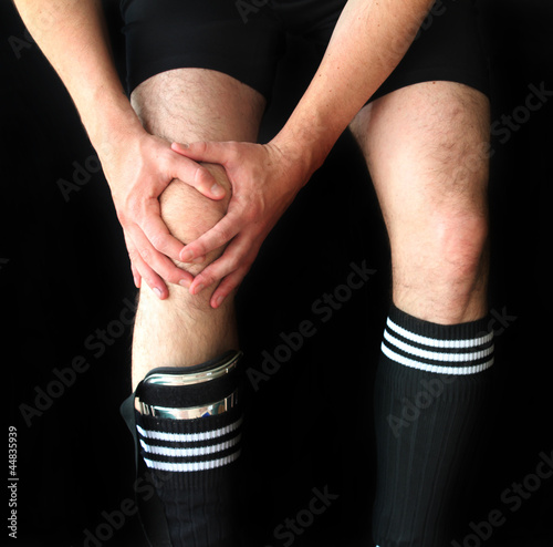 Photo: soccer male player holding injured knee soccer male player holding injured knee