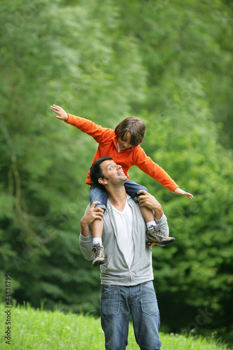 Photo: Little boy sat on father's shoulders Little boy sat on father's shoulders