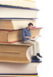 Man sitting on a stack of books and using laptop