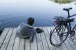 Young businessman relaxing on pier at lake with bicycle