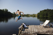Young man jumping in lake from pier