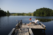 Young businessman sitting on pier at lake with German flag