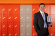 Smiling teacher holding paperwork near school lockers