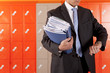 Teacher holding paperwork near school lockers and checking the time