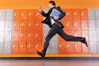 Serious teacher holding paperwork running past school lockers