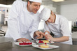 Chef teaching trainee how to garnish gourmet dessert in commercial kitchen