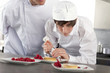 Photo: Chef teaching trainee how to garnish gourmet dessert in commercial kitchen Chef teaching trainee how to garnish gourmet dessert in commercial kitchen