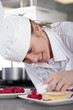 Trainee chef wiping gourmet dessert in commercial kitchen