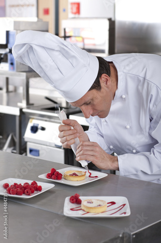 Photo: Chef decorating gourmet dessert in commercial kitchen Chef decorating gourmet dessert in commercial kitchen