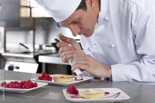 Photo: Chef decorating gourmet dessert in commercial kitchen Chef decorating gourmet dessert in commercial kitchen
