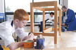 Student in woodworking class carefully putting stain on wooden table