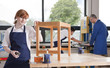 Student in woodworking class putting stain on wooden table