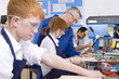 Teacher watching students use saw in woodworking class