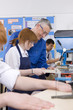 Teacher watching students use saw in woodworking class