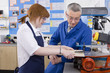 Teacher watching student use saw in woodworking class