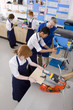 Teacher watching students use saw in woodworking class