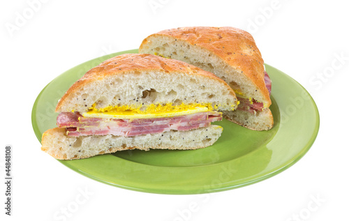 Photo: Cut capicolla sandwich on green plate Cut capicolla sandwich on green plate
