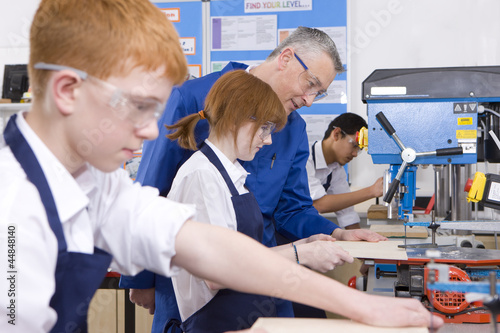 Photo: Teacher watching students use saw in woodworking class Teacher watching students use saw in woodworking class